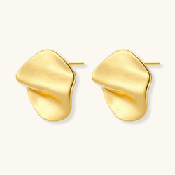 Close-up of organic gold-plated sterling silver stud earrings with flowing sculptural design and curved cut-outs
