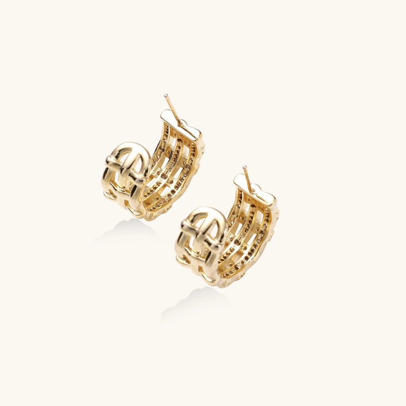 Gold-plated geometric hoop earrings with basket-weave lattice design and pavé crystal accents on cream background
