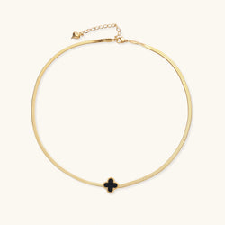 Dainty 18K gold-plated herringbone chain necklace with black enamel quatrefoil clover pendant on white background