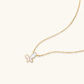 Gold-plated butterfly pendant with iridescent mother of pearl inlay on delicate chain against cream background.