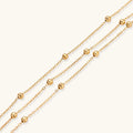 Three-strand gold-plated bracelet with clustered ball beads and adjustable clasp on cream background