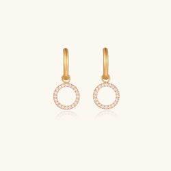 Gold-plated huggie hoop earrings with CZ-studded open circle charms on beige background