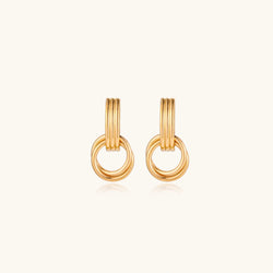 Gold stud earrings with vertical ridged bar connecting to triple interlocking circular rings on white background