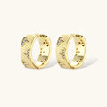 Gold-plated hoop earrings with textured surface and raised floral motifs set with clear zirconia stones on cream background.
