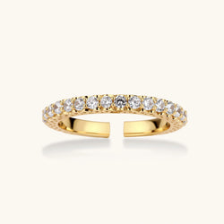 Close-up of adjustable gold-plated ring with continuous row of round zirconia stones on neutral background.