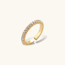 Close-up of adjustable gold-plated ring with continuous row of round zirconia stones on neutral background.
